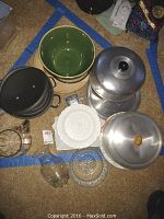 Overview of multiple kitchenware items including ceramic bowls, metal pans, a cake stand with cover, and several glass plates and bowls.