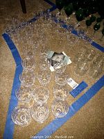 Multiple clear cut crystal glasses in three sizes displayed on carpet