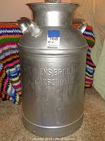 Front view of large metal milk jug showing embossed Stephens Bros Dairy Carbondale markings and side handles.