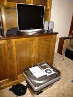 Sony 17 inch computer monitor on cabinet with Dell keyboard and speakers on top, ION USB turntable with manuals and headphones on floor