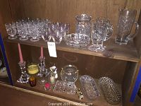 Shelf showing assorted crystal glassware including dessert cups, pitchers, ashtrays, candlestick holders, and votives.