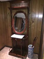 Full front view showing hall tree with mirror, marble top, drawer, hooks, vase and canes