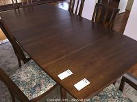 Full view of the rectangular Broyhill dining table with wooden frame showing a medium brown finish and some wear on the surface.