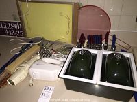 Overview of assorted kitchen items including hand mixer, silverware, plastic cutting boards, hot plate, and covered containers.