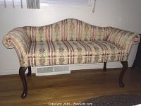 Front view of upholstered settee with floral stripe pattern and wooden legs.