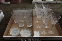 Set of 8 champagne flutes, 8 water glasses, and 6 coasters arranged in a box; shows all items included in the lot