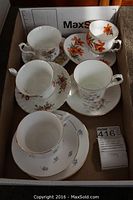 Five assorted floral bone china cups and saucers with gold trim inside shipping box