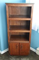 Front view showing entire wooden shelving unit with three shelves and two doors at bottom
