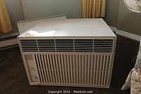 Front view of beige Wall Mate air conditioner unit showing front vents and control knobs.