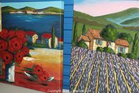 Two acrylic photo prints side by side, one with red flowers and houses by water, other with lavender field and house