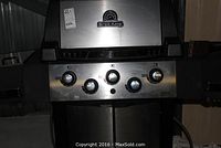 Front view of grill with lid closed showing Broil King badge and five control knobs