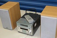 Front view of the Sony stereo system with remote placed on top and two wood grain speakers side by side.