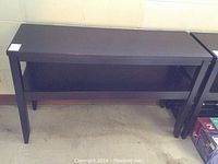 Full view of the black sofa or entry table showing the front panel and lower shelf