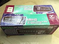Photo of the boxed MM4D four channel powered box mixer with digital effects unit showing box design and branding.