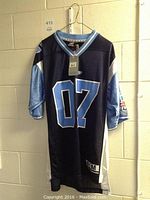Front view of navy blue, light blue, and white Toronto 2007 Grey Cup jersey with large '07' on chest, hanging on wire hanger.
