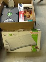 Photo showing original Xbox console and stored game cases including Hell's Kitchen Wii game.