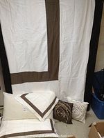 Full view of king size duvet cover white with chocolate trim and accompanying pillow shams and decorative pillows.