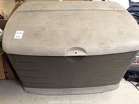 Front view of large gray Rubbermaid storage bin with hinged lid showing surface dirt and overall condition.
