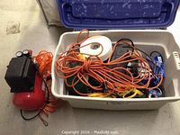 Jobmate 3 gallon air compressor and plastic storage bin filled with orange extension cords, power strips, and other small items including a white hard hat.