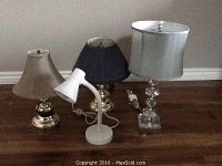 Four bedside table lamps of various finishes displayed on floor