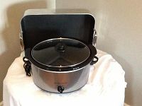 Photo of a stainless steel Paderno roaster with lid, alongside a Hamilton Beach slow cooker model 33550 on a white cloth background.