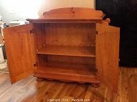 Front view of oak storage cabinet with doors open showing two interior shelves and wooden construction.
