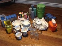 Full view of assorted kitchenware, plates, glasses, mugs, pitchers, and many plastic storage containers mostly Tupperware style.