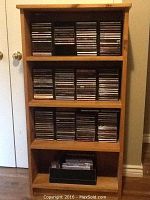 Full view of wooden bookcase with shelves holding CDs and DVDs.