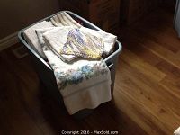 Full view of a large grey Rubbermaid bin filled with folded bath towels, hand towels, and fabric oven mitts.