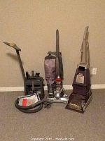 Photo showing Kirby Sentria vacuum cleaner with hose, accessories, manual and CD set together with Hoover SteamVac upright cleaner.