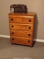 Wood bureau with four drawers and a cushioned upholstered foot stool on top