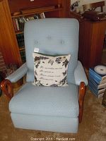 Full view of the light blue upholstered reclining rocking chair with wooden armrests and attached seat cushion, showing general condition and structure.
