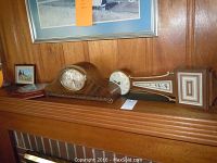 Three clocks displayed on a wood mantel. Two mantle clocks with different shapes: a curved tambour design and a long rectangular clock with decorative front panels.