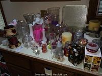 Countertop with glass vases, Fenton glass bears, glass bells, and assorted candles including Yankee Candle jars.