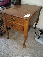 Photo of one oak veneer end table showing two brass-handled drawers, cabriole legs, and minor surface wear.