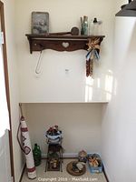 Wide shot of the rustic wooden wall shelf with heart cut-out and assorted items below including green glass bottle, woven basket, and smaller decor items.