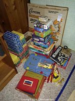Photo of stacked vintage board games, cardboard building blocks, Sure Shot Ice Hockey table game and Battleship game case.