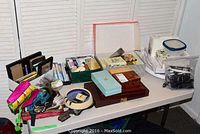 Wide view of assorted boxed personal items, photo frames, lighters, and party ware on table