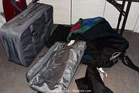 Full view showing large grey suitcase, matching hanging suit bag, colorful ski bag, snowboard bag, black wheeled duffle bag, and small black briefcase with visible wear