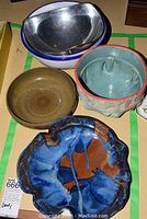 Five bowls including a large silver metal alloy Nambe tri-corner bowl and four pottery bowls in varying colors and textures.