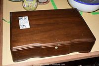 Closed dark wood hinged flatware chest with paper label reading 'silver plate' on lid