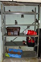 Full view of one metal shelving unit with items including a brown basket, plastic bag, tool bag, and cardboard box on shelves