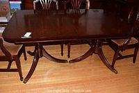 Top view of rectangular Duncan Phyfe style dining table with dark wood finish showing surface wear and scratches. Three leaves included to extend table length.