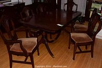 Six dining chairs (two arm chairs and four side chairs) arranged around dining table