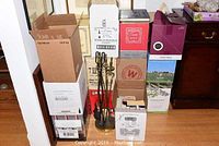 Multiple cardboard boxes stacked, containing books of various subjects including science fiction and 'Collected Coins'. Boxes are a mix of plain and labeled wine packaging boxes.