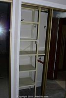 Metal shelving unit in closet space showing six shelves and metal frame.