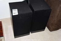 Front and side view of two black Castle Durham speakers with fabric covers.