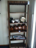 Front view of the dark tone carved five tiered solid oak etagere showing all shelves with various items (contents not included).