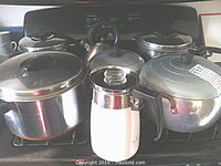 Front view of all pots and percolator, showing lids, handles, and varying sizes including Ekcoware pots and other cookware.