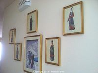 Six traditional Asian fashion prints on a wall, five small Chinese figure prints and one large Japanese print, all framed in gilt wood.